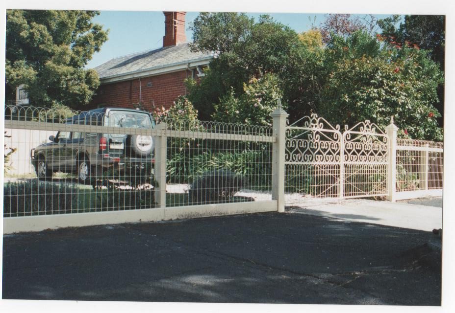 Ornamental fence and gates fronting a home and garden
