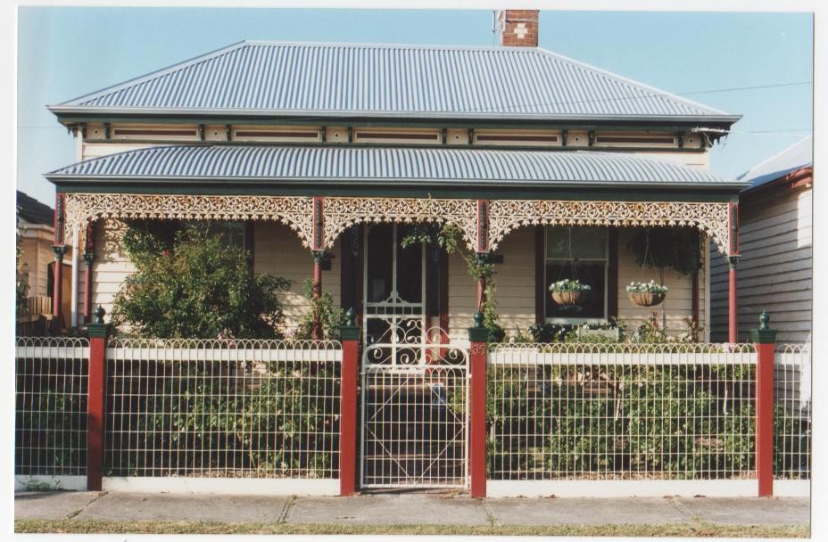Woven-wire fence with ornate gate at a brick home